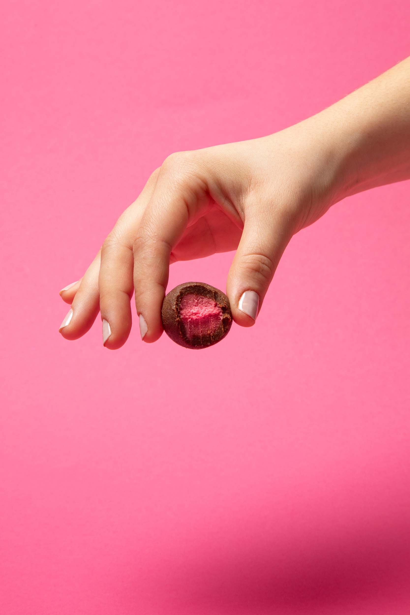 Ein veganer Frozen Power Dattel Energy Ball mit zuckerfreier Himbeereis Füllung und Dattelumhüllung