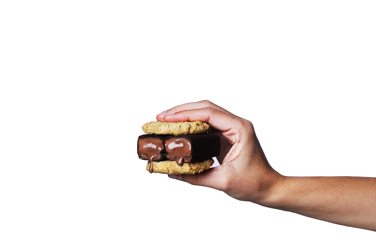 Hand hält einen gesunden Snack mit zwei Keksen und einem Schokoladen-Protein Eis-Riegel von Frozen Power