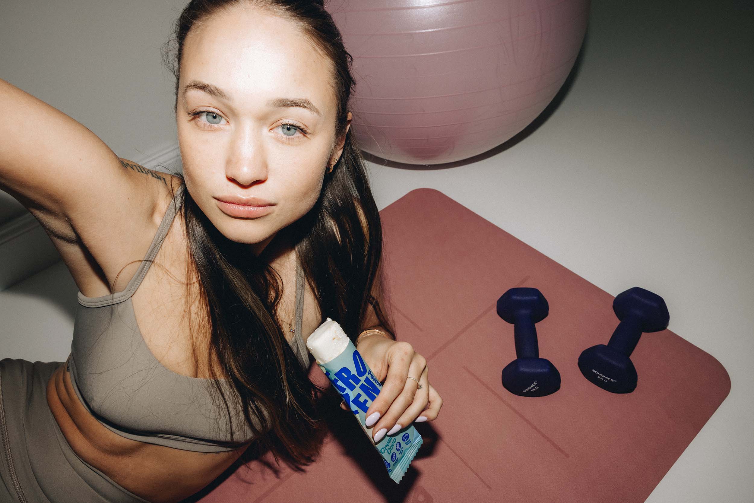 Frau hält nach dem Sport einen High Protein Eis-Riegel in der Sorte Creamy Coco in der Hand