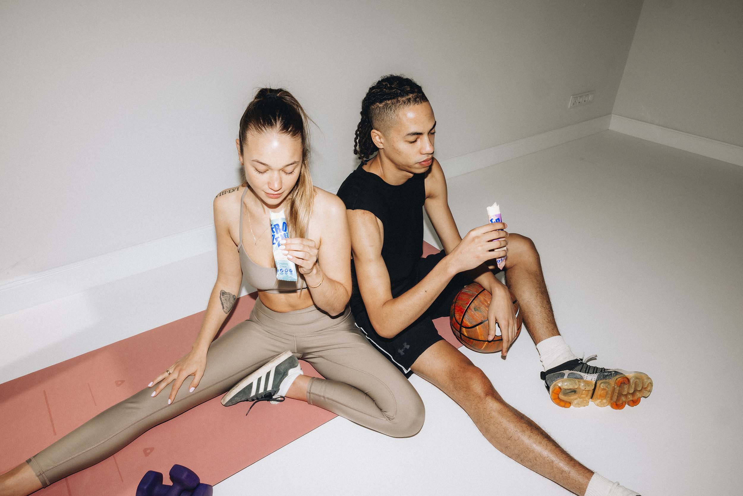 Zwei Sportler holen sich einen Protein Kick nach dem Training mit dem Frozen Power Protein Eisriegel in der Sorte Creamy Coco und Yogurt Amarena ohne Zuckerzusatz