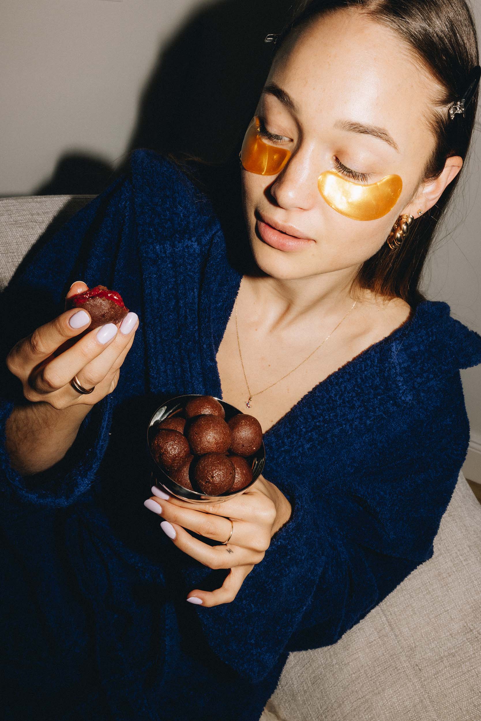 Eine Frau isst einen veganen Snack ohne Zuckerzusatz und hält eine Schale gesunder Dattel Energy Bällchen von Frozen Power in der Sorte Himbeere in ihrer Hand.